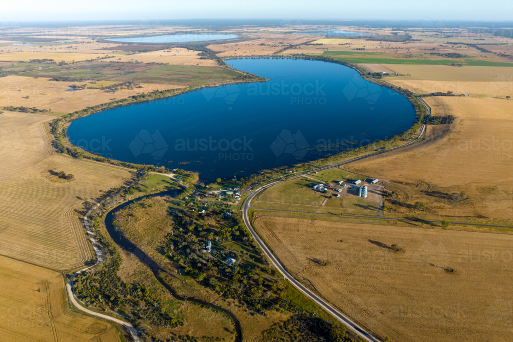 Aerial view of lake surrounded by farmland and rural settlement. - Australian Stock Image