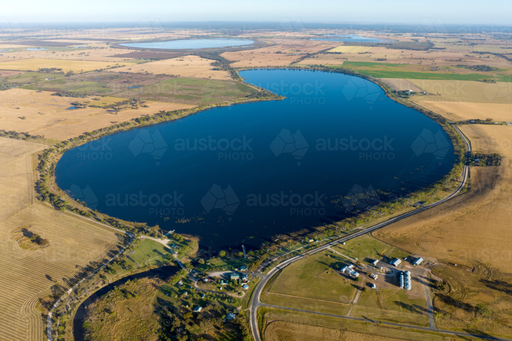 Aerial view of lake surrounded by farmland and rural settlement. - Australian Stock Image
