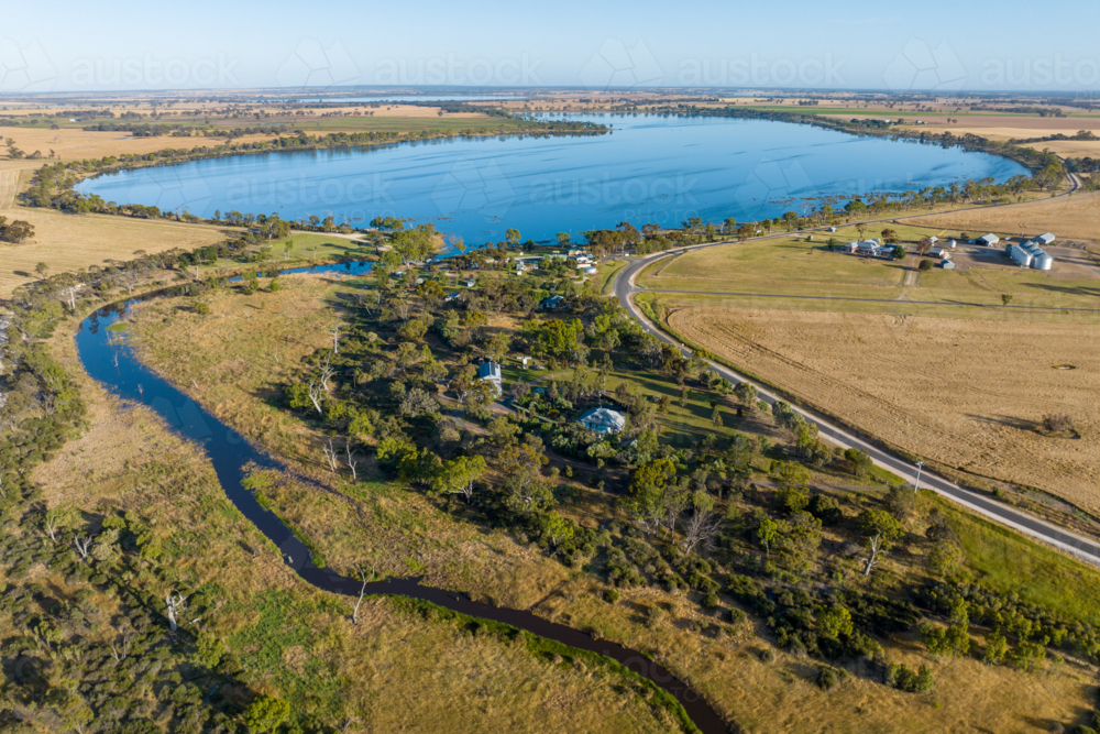 Aerial view of lake surrounded by farmland and rural settlement. - Australian Stock Image