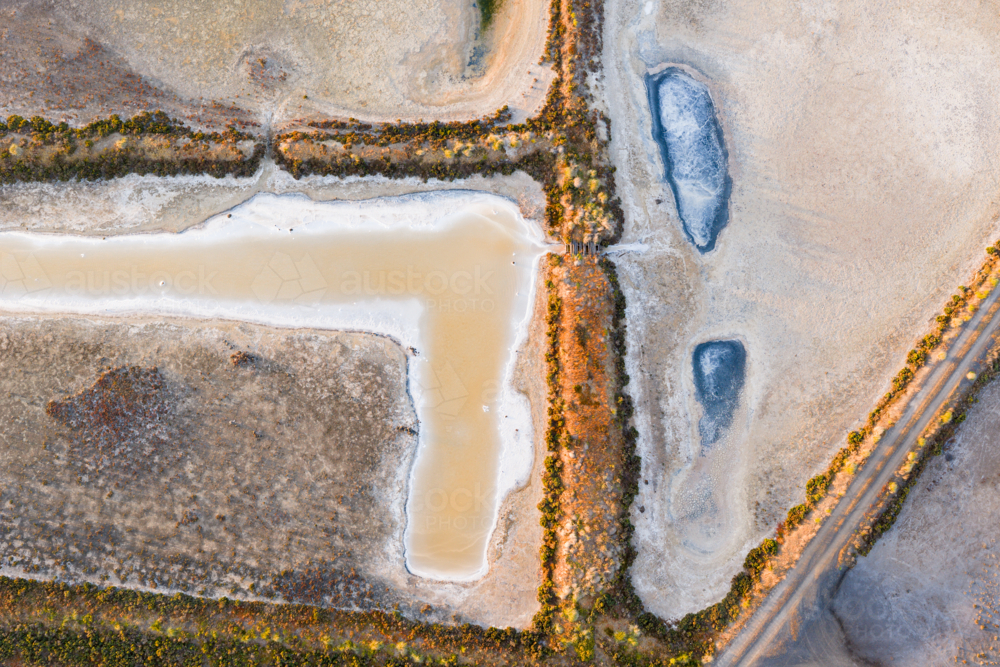 Aerial view of levee banks and colourful evaporation ponds at a coastal salt works - Australian Stock Image