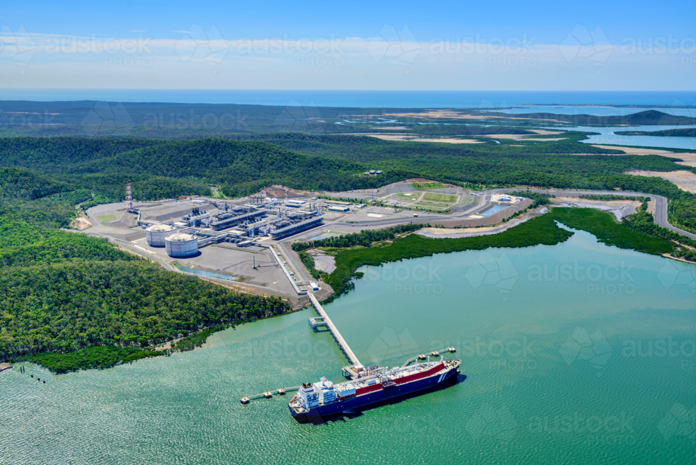Aerial view of liquified natural gas plant and LNG ship docked at a long pier - Australian Stock Image
