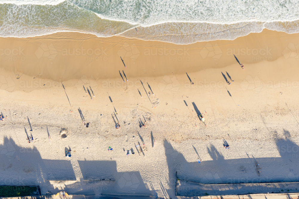 Aerial view of long shadows from beachgoers on a wide sandy beach - Australian Stock Image