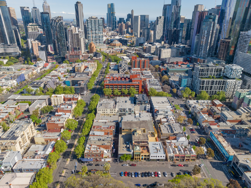 Aerial view of low urban buildings in blocks in front of a highrise city skyline - Australian Stock Image