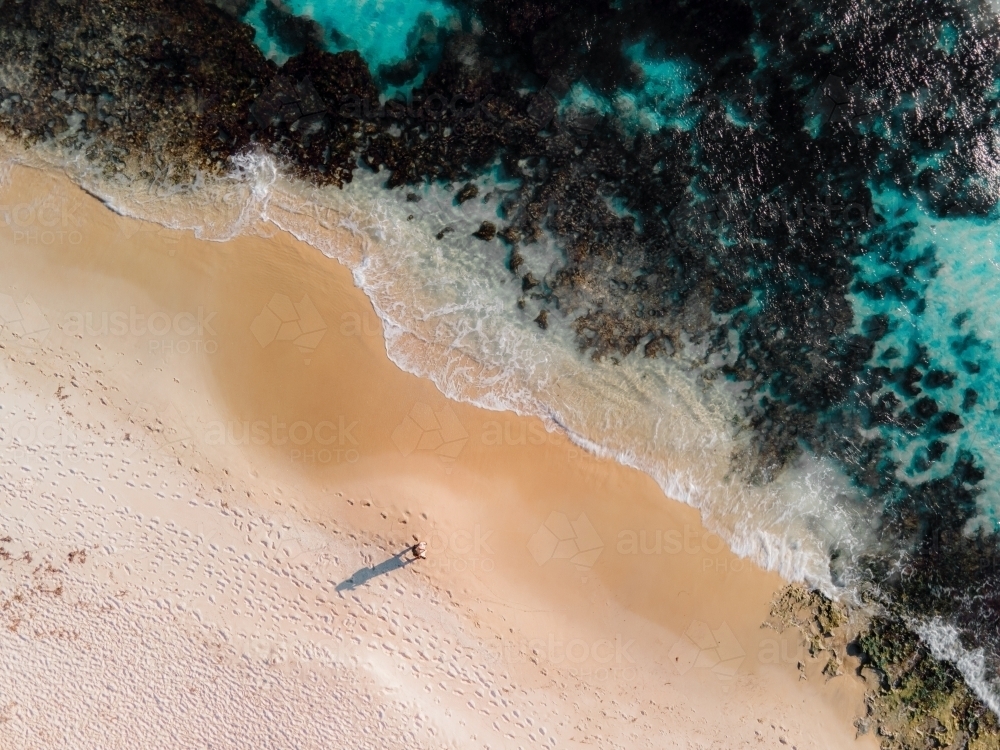 Aerial view of one person walking along sand next to reef on North Beach, WA - Australian Stock Image