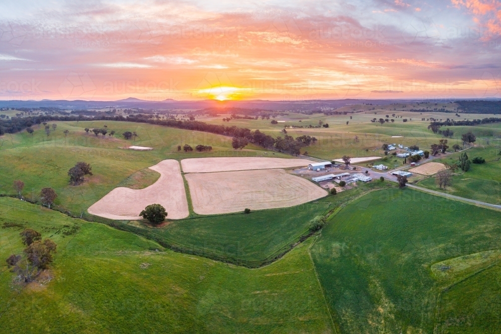 Aerial view of ploughed paddocks near farm buildings at sunset - Australian Stock Image