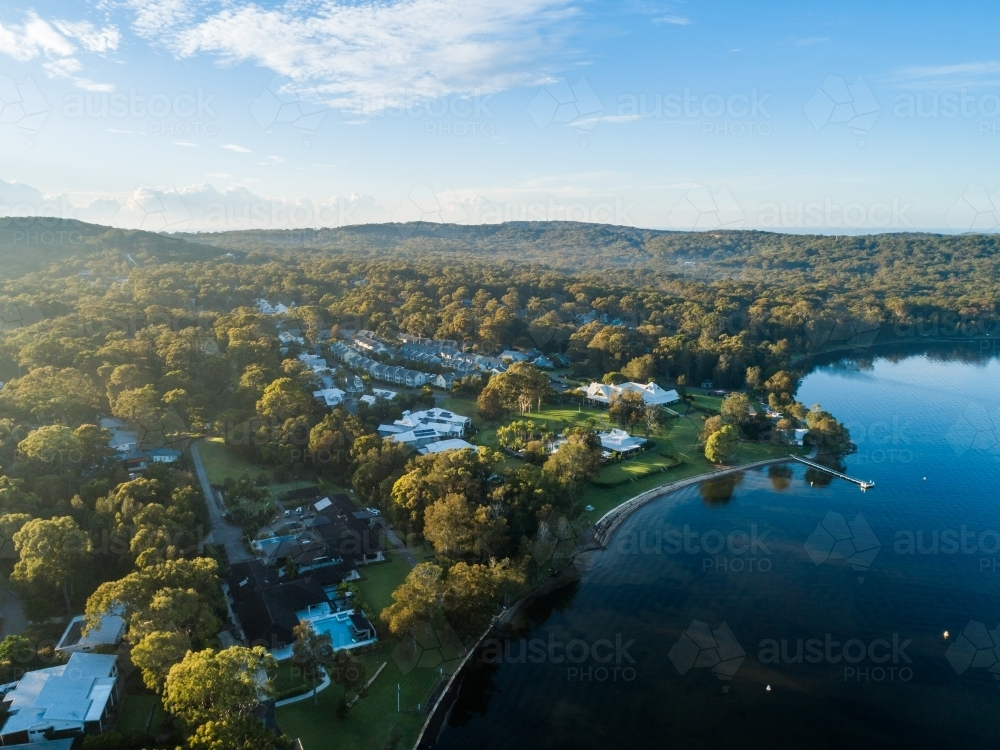 Aerial view of Raffertys Resort Cams Wharf beside lake in morning light - Australian Stock Image