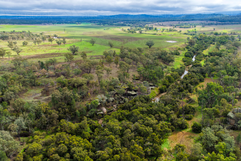 Aerial view of Reedy Creek winding through the granite rock formations and lush green bushland - Australian Stock Image
