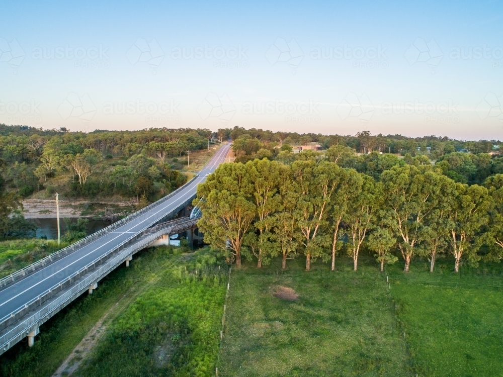 Aerial view of road and bridge over floodplain farmland in sunset light - Australian Stock Image