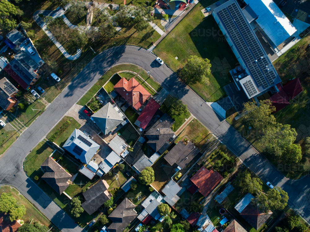 Aerial view of road looping through suburb in town on sunlit morning in summer - Australian Stock Image