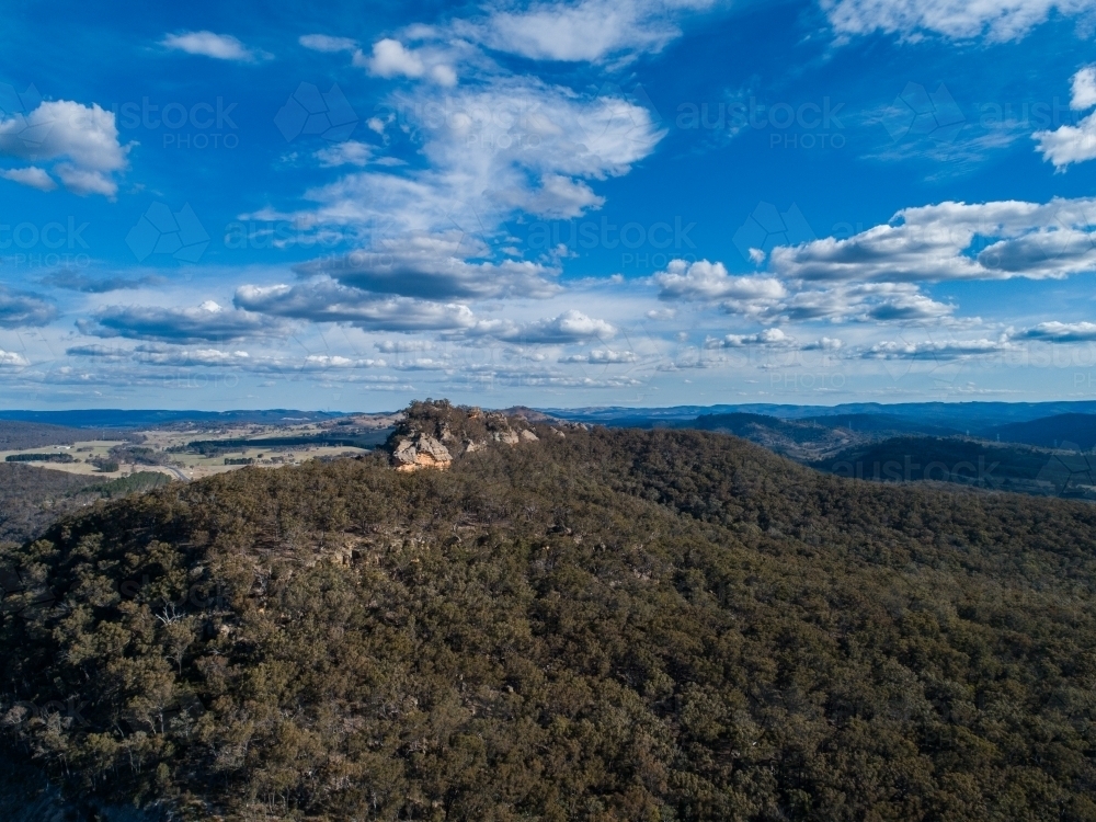 Aerial view of rocky cliff outcrop on hilltop at midday - Australian Stock Image