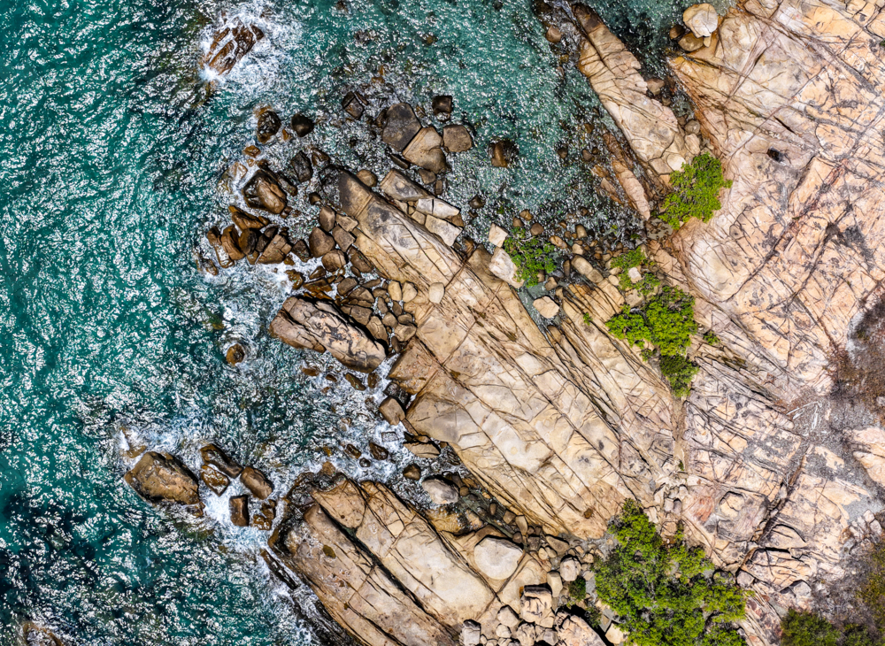 aerial view of Rose Bay in Bowen, Queensland, showcasing turquoise waters and rocky shoreline - Australian Stock Image