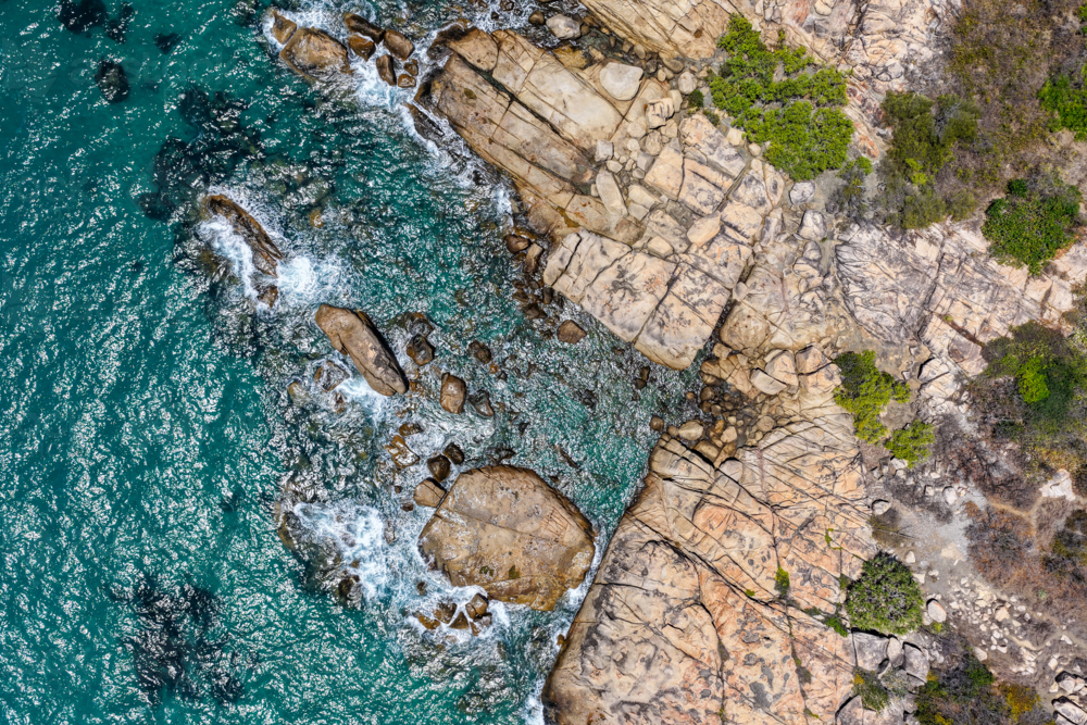 aerial view of Rose Bay in Bowen, Queensland, showcasing turquoise waters and rocky shoreline - Australian Stock Image