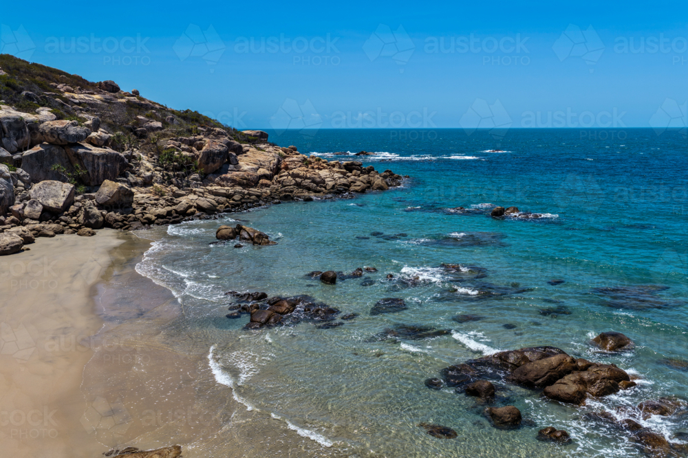 Aerial view of Rose Bay in Bowen, showcasing its shoreline, turquoise waters and rocky headland - Australian Stock Image