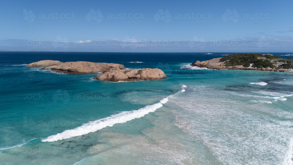 Aerial view of rounded boulders in a shallow turquoise sea water - Australian Stock Image