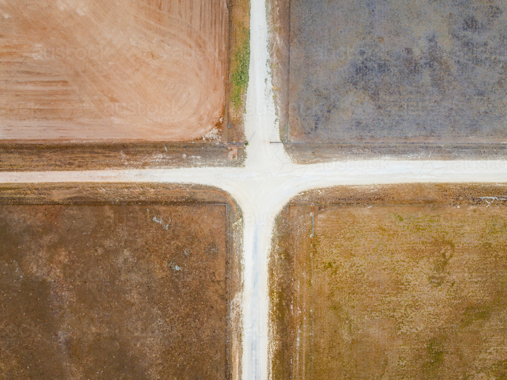 Aerial view of rural crossroad with barren paddocks alongside - Australian Stock Image