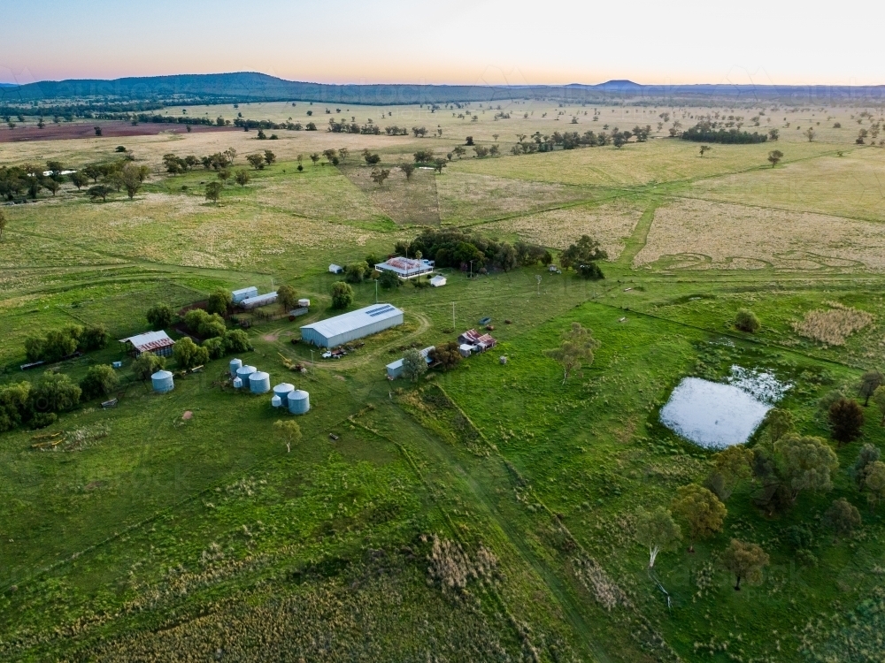 Aerial view of shed and silos, dam and green paddocks with homestead - Australian Stock Image