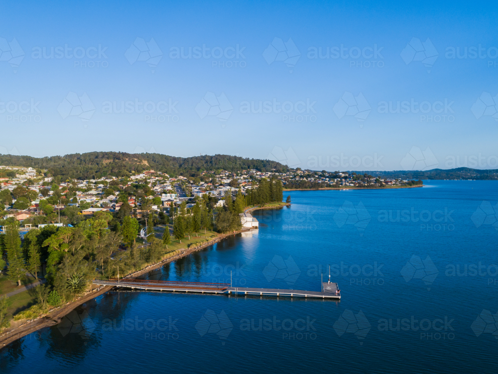 Aerial view of Speers Point Public Jetty in sunlit blue waters of Lake Macquarie and Cockle bay - Australian Stock Image