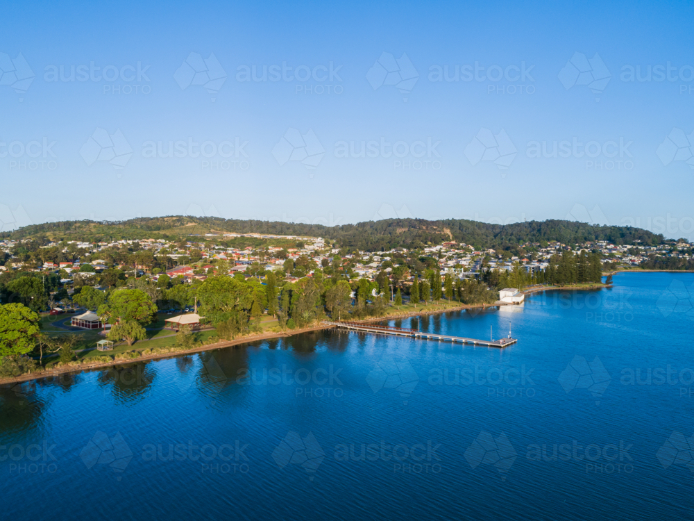 Aerial view of Speers Point Public Jetty in sunlit blue waters of Lake Macquarie and Cockle bay - Australian Stock Image