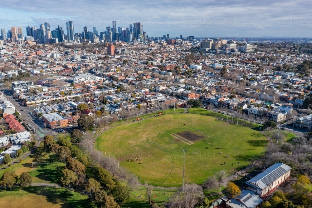 Aerial view of sports ovals in a suburban park with city skyline in the distance - Australian Stock Image