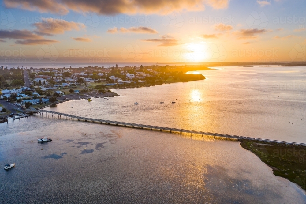 Aerial view of sunset over a coastal town and bridge over a bay - Australian Stock Image