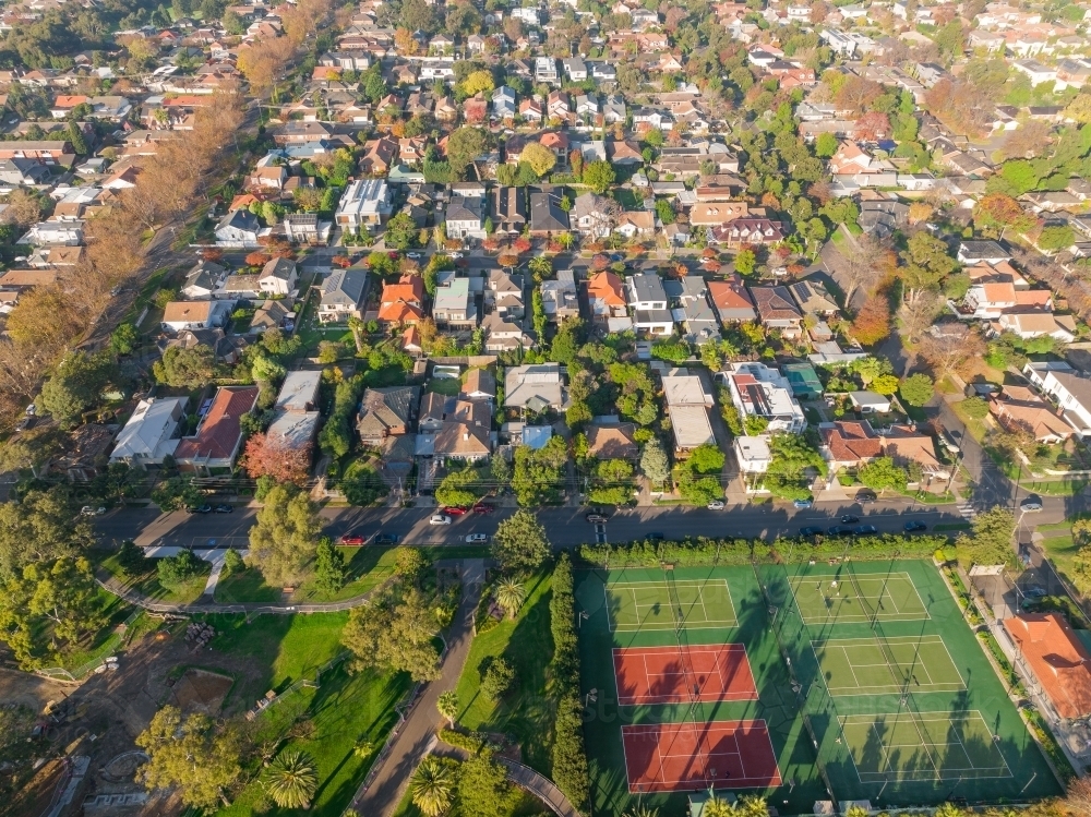 Image of Aerial view of tennis courts and parkland alongside suburban