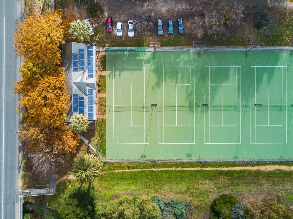 Aerial view of tennis courts with solar panels on the roof of the clubrooms and Autumn trees - Australian Stock Image