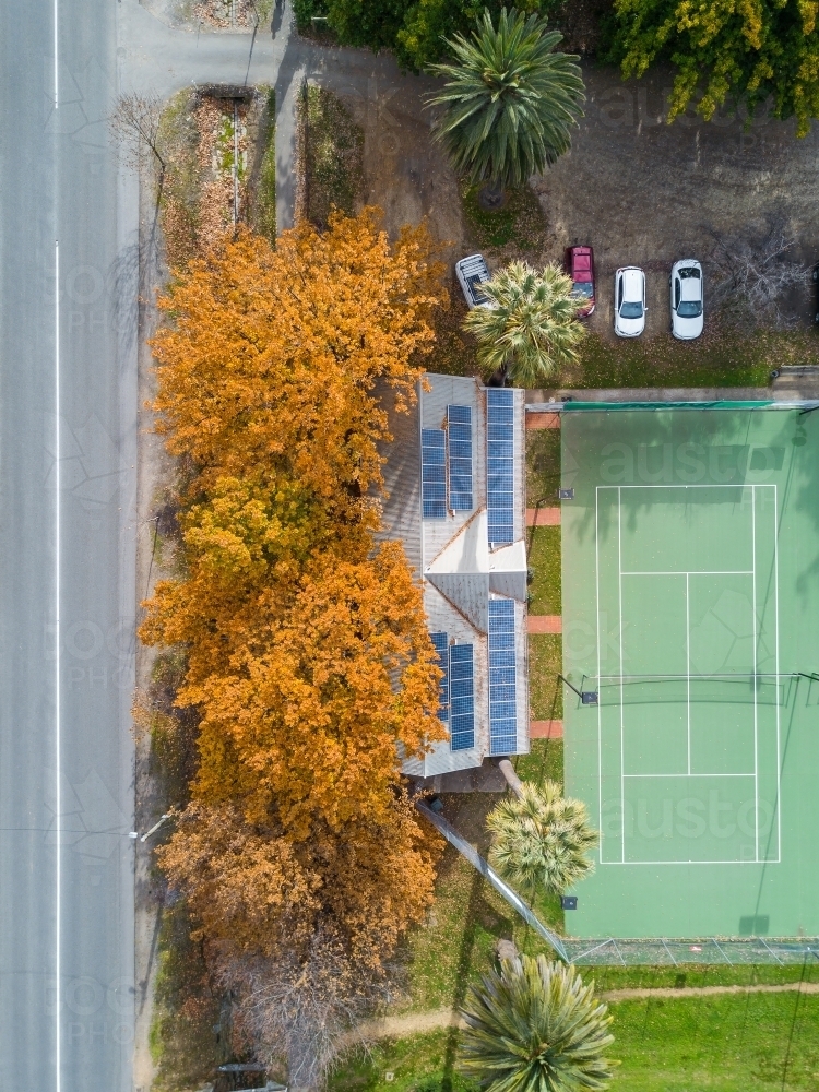 Aerial view of tennis courts with solar panels on the roof of the clubrooms and Autumn trees - Australian Stock Image
