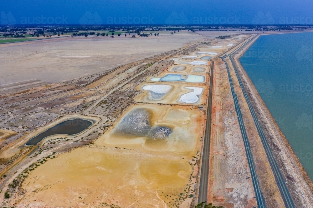 Aerial view of the dam wall and evaporation ponds of a large reservoir. - Australian Stock Image