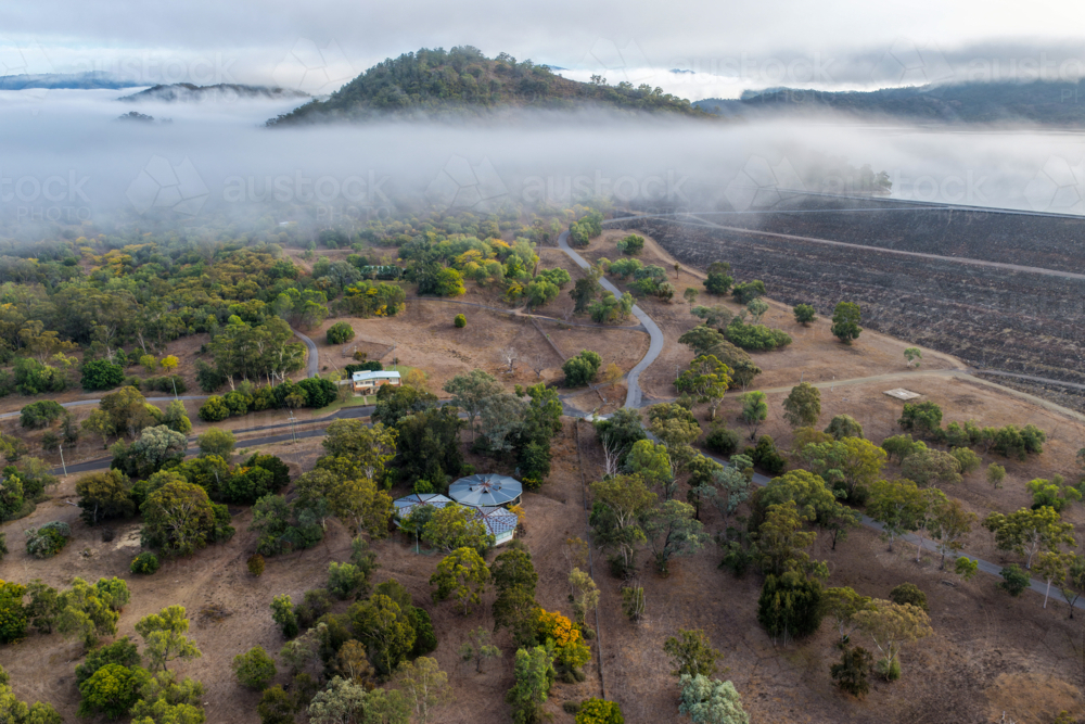 Aerial view of the Glenbawn Dam wall and surrounding landscape with fog rolling through the valley - Australian Stock Image