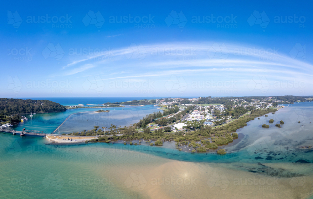 Aerial view of the idyllic coastal town of Narooma at sunset wrapped around the famous Wagonga Inlet - Australian Stock Image