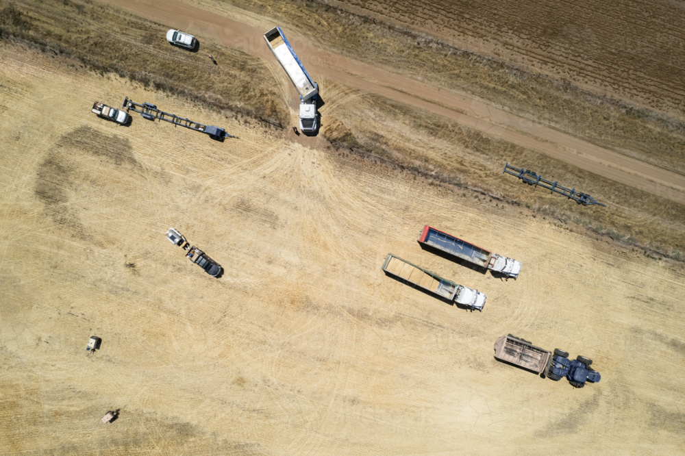 Aerial view of transport trucks and combine harvester on the field - Australian Stock Image