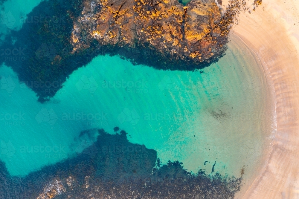 Aerial view of turquoise water in a large rockpool and a sheltered sandy beach - Australian Stock Image