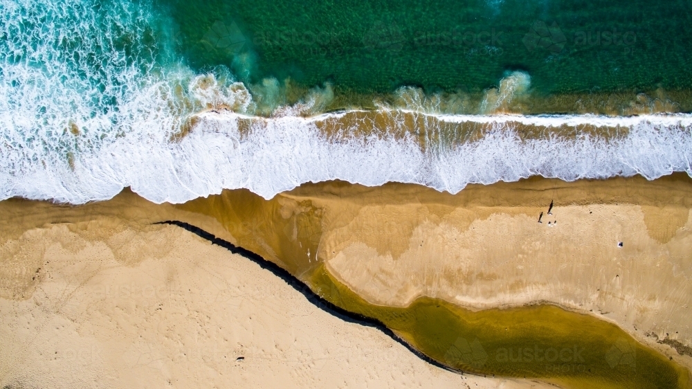 Aerial view of two men surf fishing from the beach as waves crash on the shore - Australian Stock Image