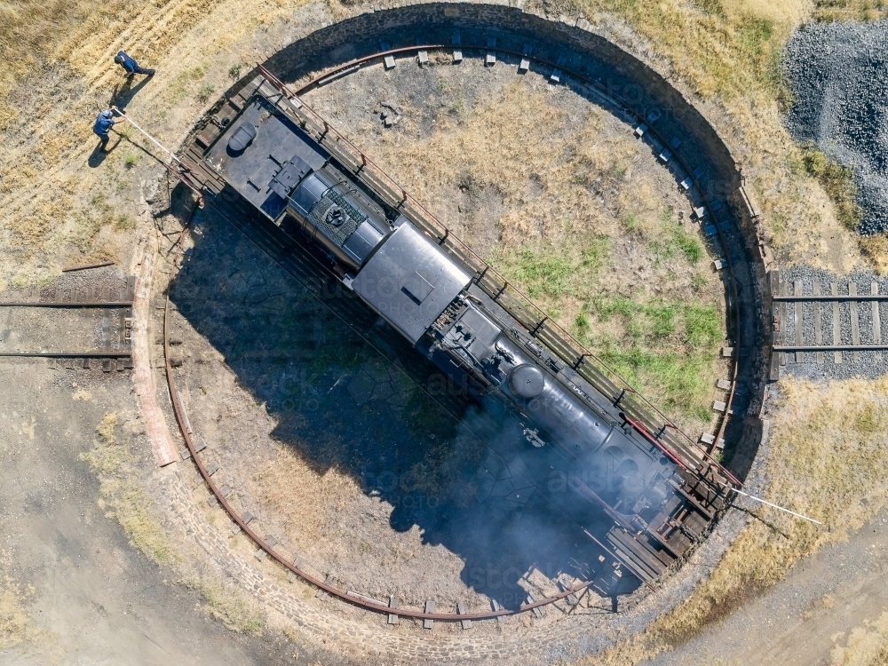 Aerial view of two train drivers pushing a steam engine around on a turntable - Australian Stock Image