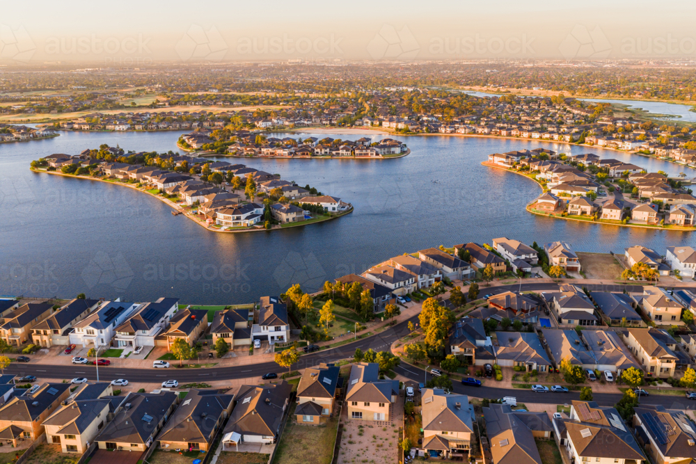 Aerial view of waterfront housing around the shoreline of a lake in late afternoon sunshine - Australian Stock Image