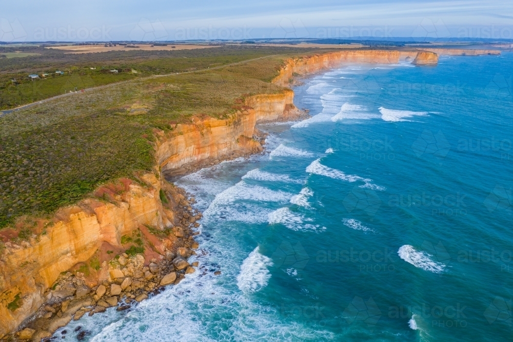 Aerial view of waves crashing along the base of high sea cliffs - Australian Stock Image