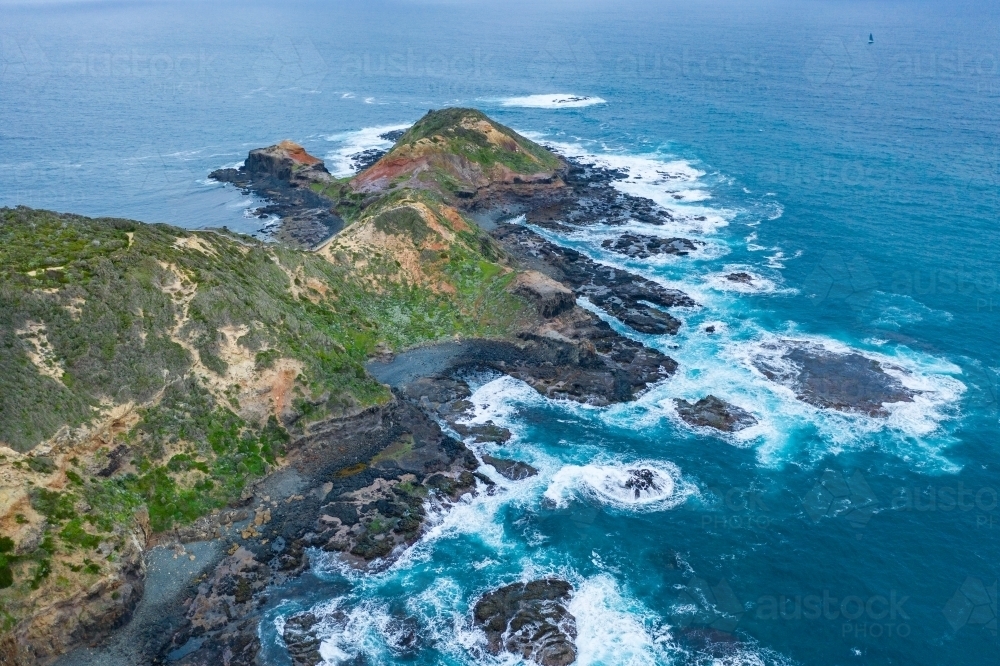 Aerial view of waves crashing on a rugged coastal peninsula - Australian Stock Image