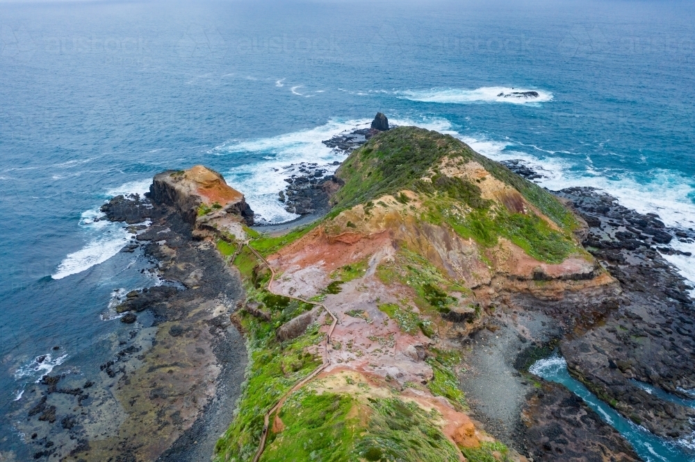 Aerial view of waves crashing on a rugged coastal peninsula - Australian Stock Image