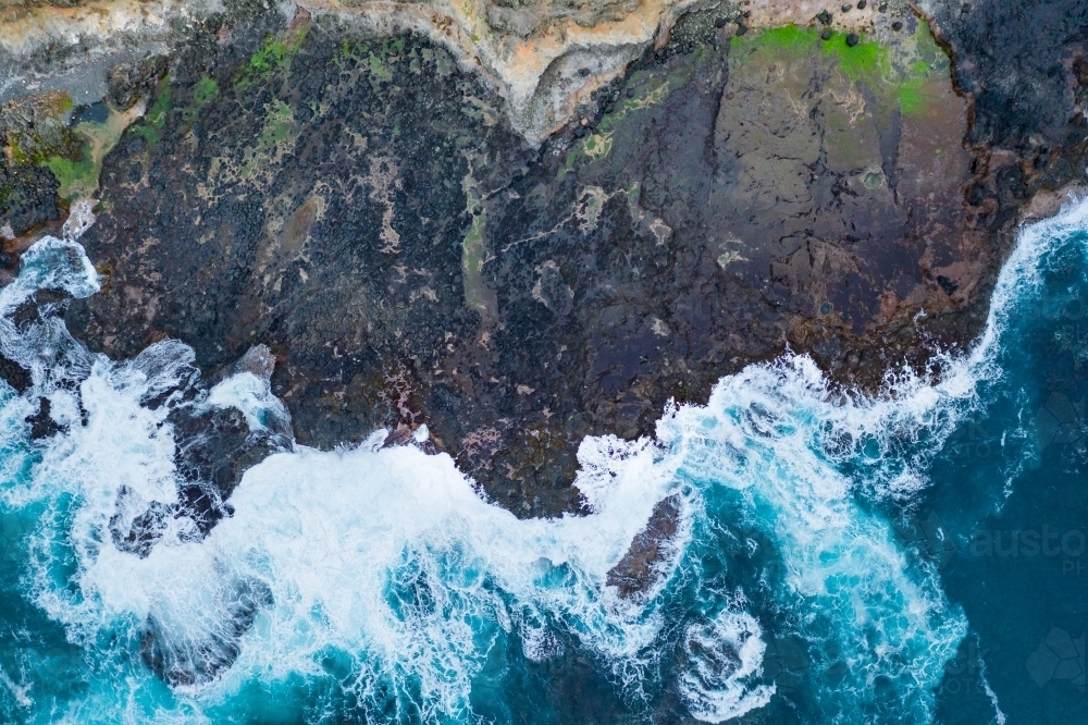 Aerial view of waves crashing on a rugged coastline - Australian Stock Image