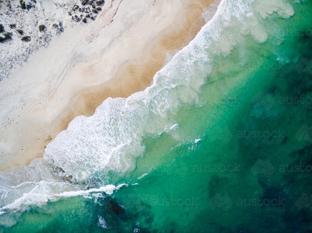 aerial view of waves washing up onto a beach - Australian Stock Image