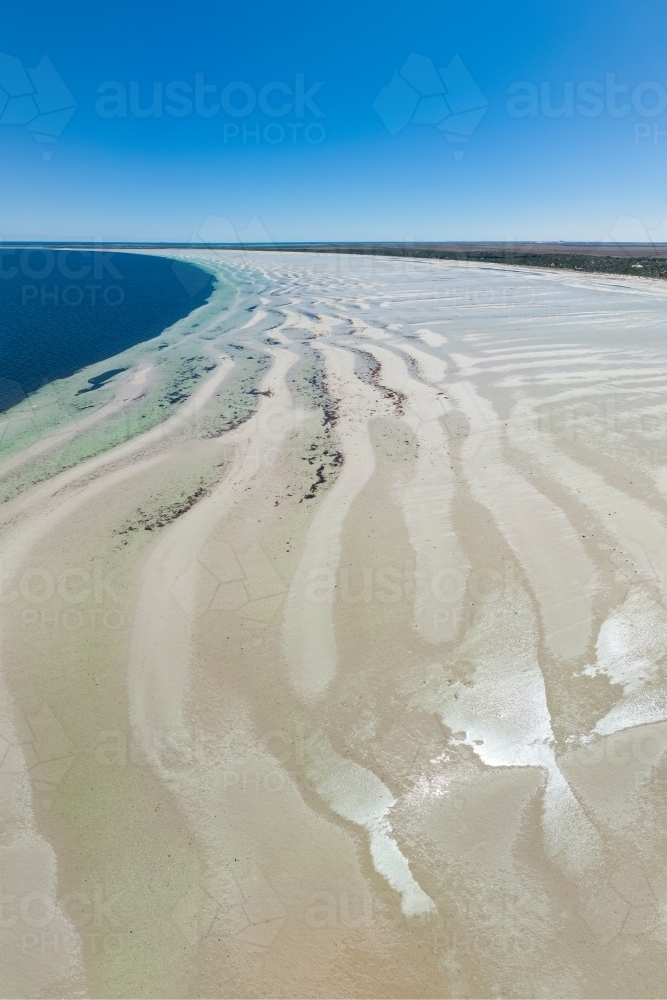 Image of Aerial view of white sand beach with ripples and pools of ...