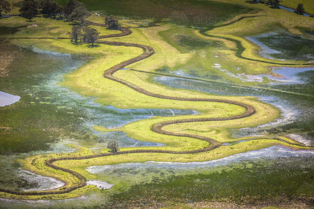 Aerial view of winding river through grassy floodplain - Australian Stock Image