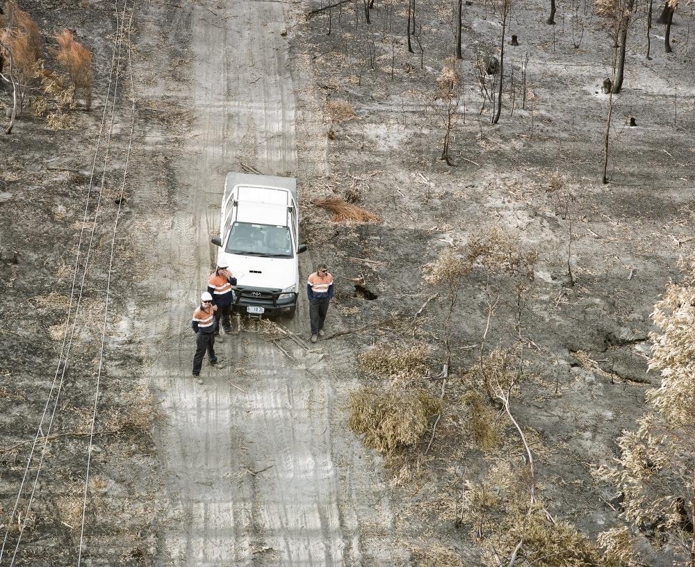Aerial view of workmen repairing power lines in bushfire ravaged landscape - Australian Stock Image