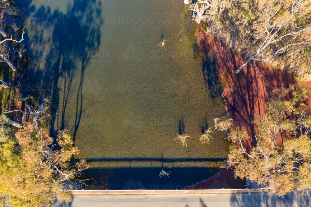 Aerial view over a bridge and river with gum trees on its banks - Australian Stock Image