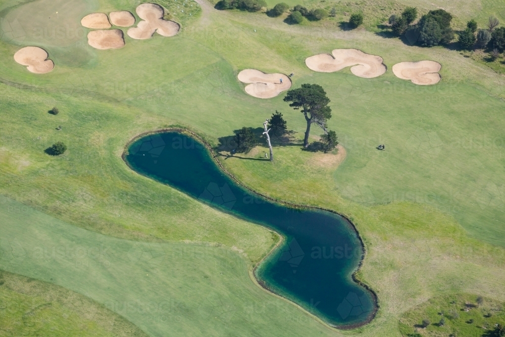Aerial view over a lake and bunkers on a golf course - Australian Stock Image