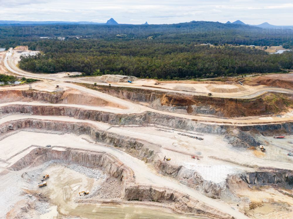 Aerial view over a quarry pit with the Glasshouse Mountains in the background - Australian Stock Image