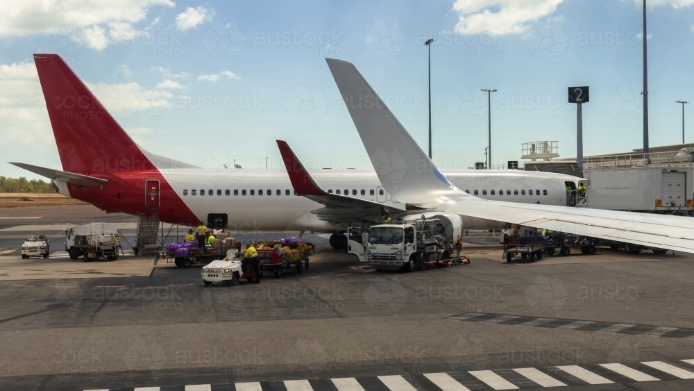 Aeroplane on tarmac at departure gate being loaded with luggage, cargo and catering supplies - Australian Stock Image