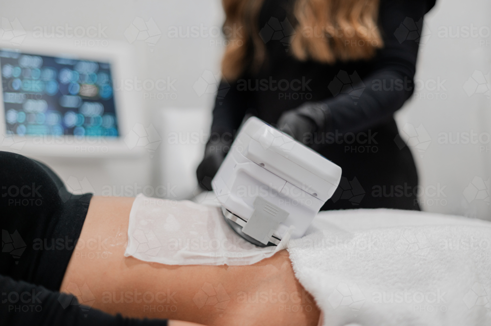 Aesthetic practitioner performing a non‑invasive body treatment on clients abdomen - Australian Stock Image