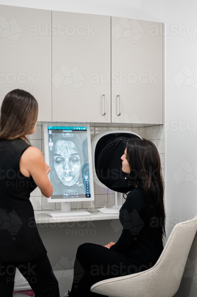 Aesthetics practitioner discussing skin analysis results during client consultation - Australian Stock Image