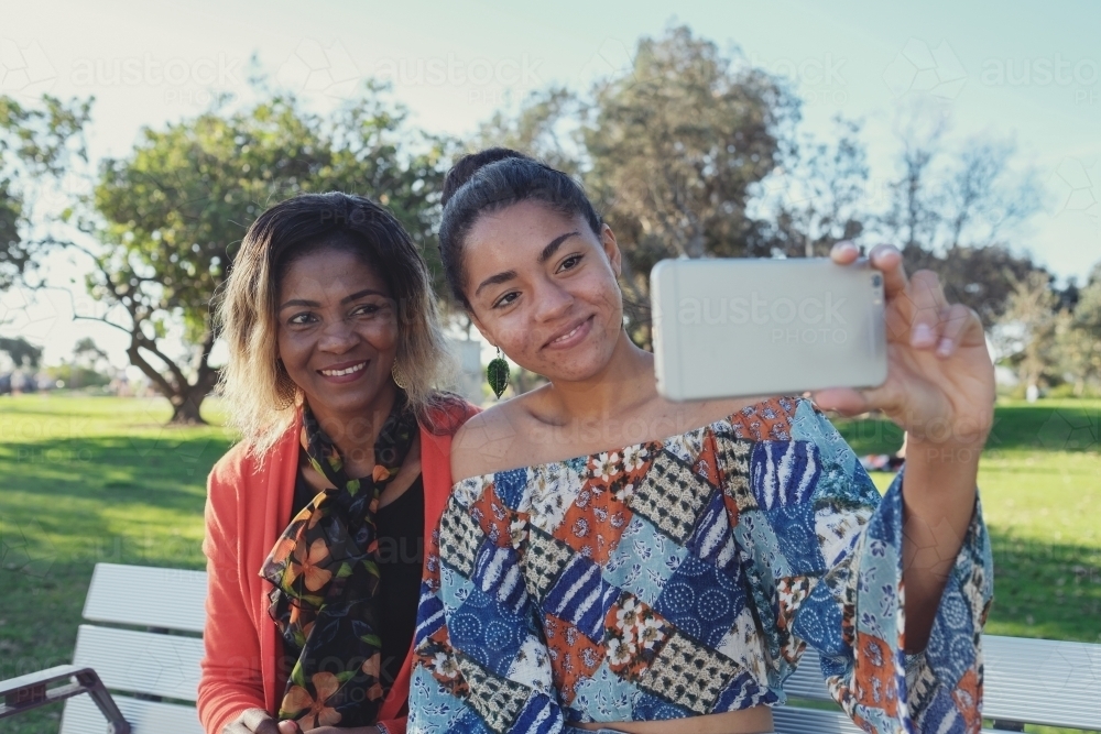 African mother and multicultural teen daughter taking selfie - Australian Stock Image
